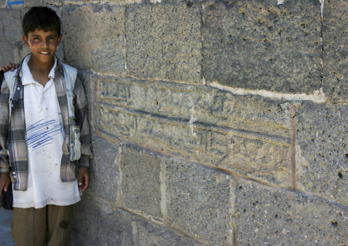 Yemeni boy near an Inscriptions on a wall of a stone building, Dhamar Governate, Dhamar, Yemen