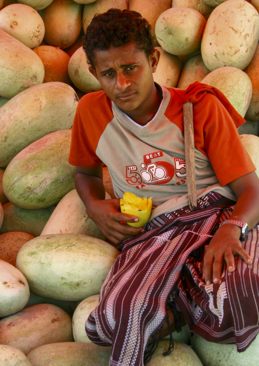 Yemeni man eating a mango in a market, Janad Region, Taiz, Yemen