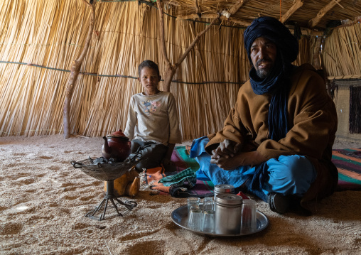 Tuareg man and son inside a reeed house preparing tea, North Africa, Tamanrasset, Algeria