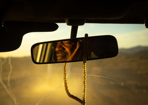 Tuareg face in a car rear view mirror with a Prayer beads, North Africa, Tamanrasset, Algeria