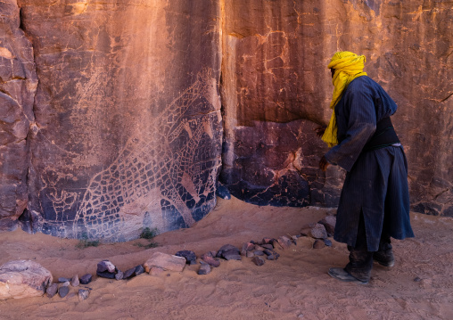 Tuareg near a rock carvings depicting giraffes, Tassili N'Ajjer National Park, Tadrart Rouge, Algeria