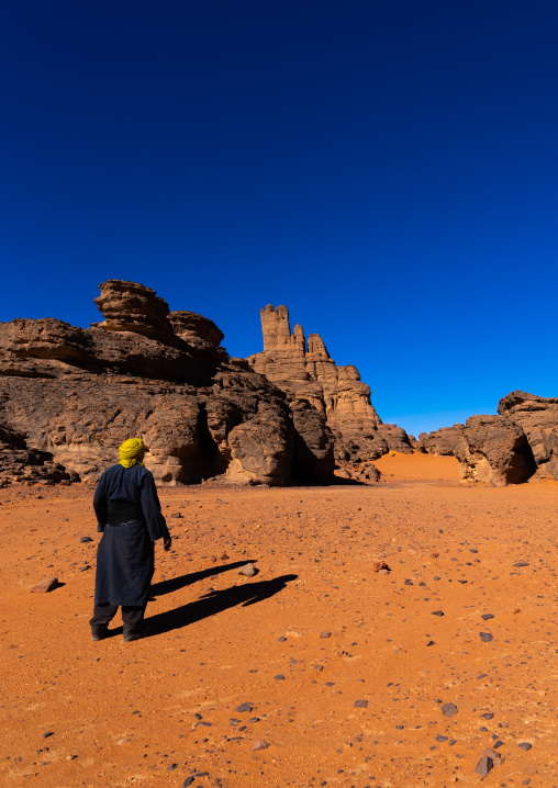 Tuaref in front of rocks and sand dunes in desert, Tassili N'Ajjer National Park, Tadrart Rouge, Algeria