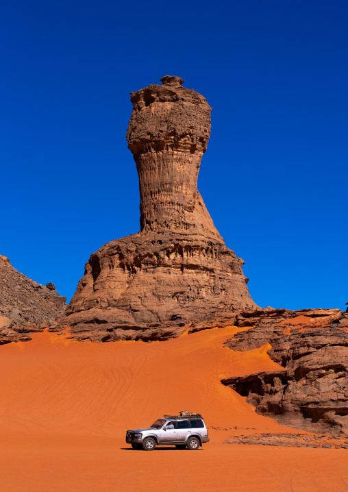 Car in front of World Cup Rock formation in Sahara desert, Tassili N'Ajjer National Park, Tadrart Rouge, Algeria