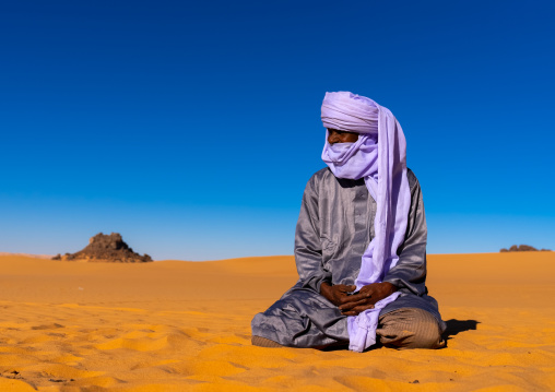Tuareg sit in the Sahara desert, North Africa, Erg Admer, Algeria