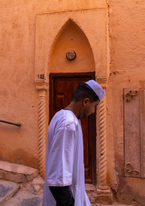 Mozabite man passing in front of an old door in Ksar El Atteuf, North Africa, Ghardaia, Algeria