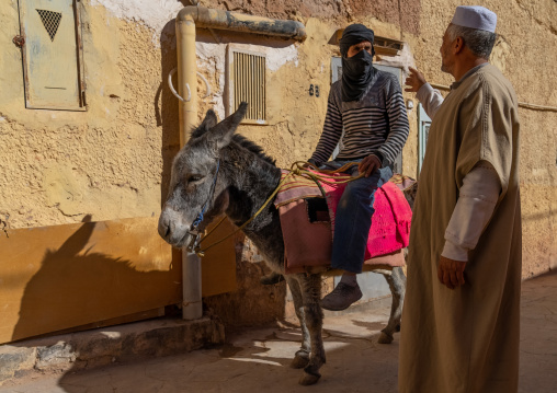 Algerian man riding a dinkey chatting with a friend, North Africa, Ghardaia, Algeria