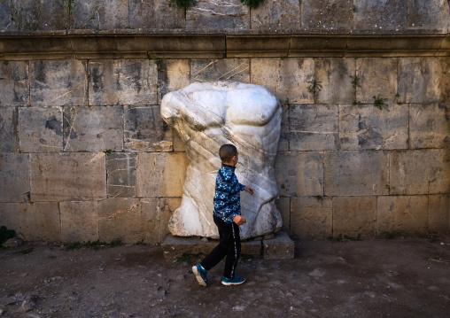 Boy near the torso of Jupiter statue, North Africa, Djemila, Algeria