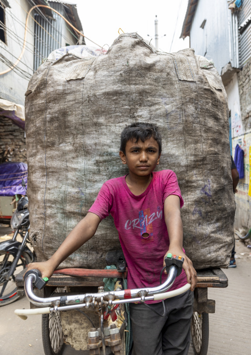 Bangladeshi boy carrying wastes to recycle on bicycle in Korail slum, Dhaka Division, Dhaka, Bangladesh