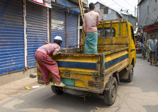 Bangladeshi boy hanging at the back of a pick-up truck in Korail slum, Dhaka Division, Dhaka, Bangladesh