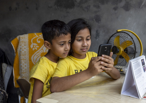 Bangladeshi boy and girl using a smartphone in Korail slum, Dhaka Division, Dhaka, Bangladesh