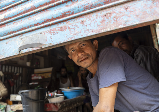 Bangladeshi man looking below an iron curtain, Dhaka Division, Dhaka, Bangladesh