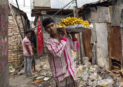 Bangladeshi man carrying bananas on his shoulder in the street, Dhaka Division, Dhaka, Bangladesh