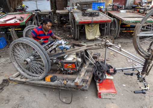 Bangladeshi mechanic repairing a rickshaw, Dhaka Division, Dhaka, Bangladesh