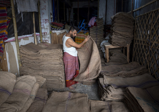 Bangladeshi man packing burlap sacks in Kawran bazar, Dhaka Division, Dhaka, Bangladesh