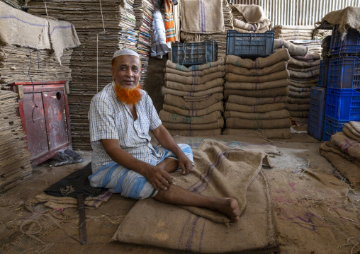 Bangladeshi man with a beard dyed in henna packing bags, Dhaka Division, Dhaka, Bangladesh