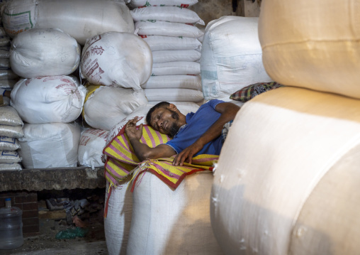 Bangladeshi man sleeping on bags in Kawran bazar, Dhaka Division, Dhaka, Bangladesh