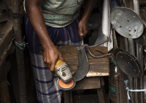 Bangladeshi man polishing blades at Kawran bazar, Dhaka Division, Dhaka, Bangladesh