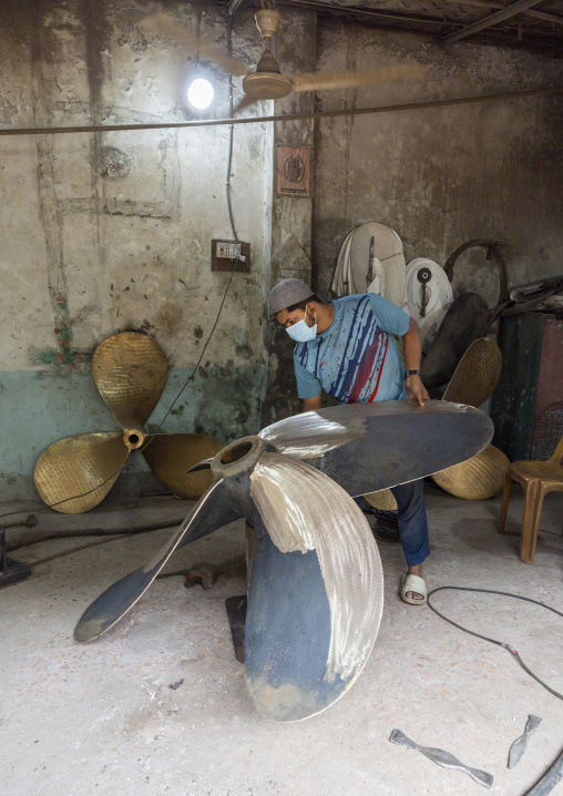 Dockyard worker polishing a propeller, Dhaka Division, Keraniganj, Bangladesh