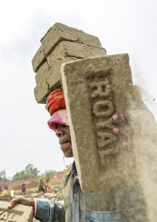 A bangladeshi man carries bricks on his head at a brick factory, Sylhet Division, Bahubal, Bangladesh