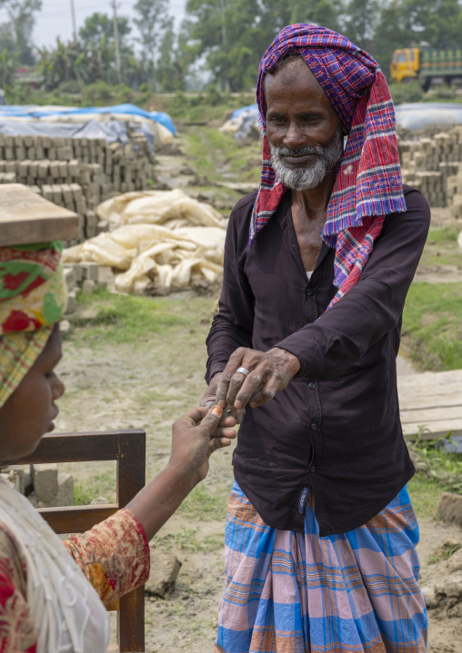 Supervisor paying a worker at a brick factory, Sylhet Division, Bahubal, Bangladesh