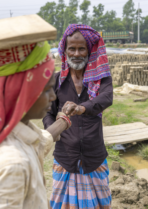 Supervisor paying a worker at a brick factory, Sylhet Division, Bahubal, Bangladesh