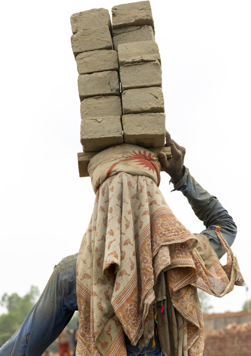 A bangladeshi man carries bricks on his head at a brick factory, Sylhet Division, Bahubal, Bangladesh