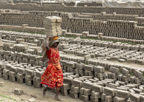 A bangladeshi woman carrying bricks on her head at a brick factory, Sylhet Division, Bahubal, Bangladesh