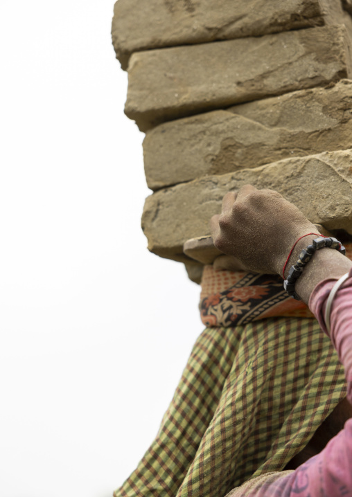 A bangladeshi woman carrying bricks on her head at a brick factory, Sylhet Division, Bahubal, Bangladesh