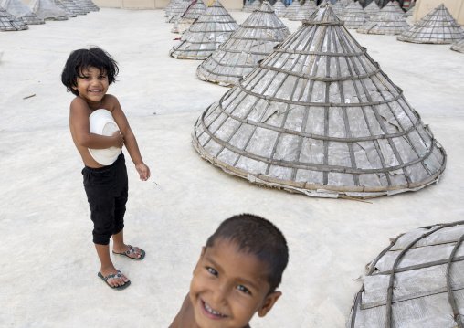 Bangladeshi children and mounds of rice with giant hat-shaped bamboo cones, Chittagong Division, Ashuganj, Bangladesh