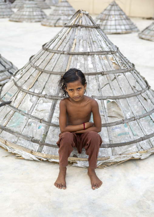 Girl sit on a mound of rice with giant hat-shaped bamboo cone, Chittagong Division, Ashuganj, Bangladesh