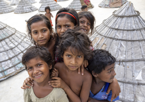 Bangladeshi children near mounds of rice with giant hat-shaped bamboo cones, Chittagong Division, Ashuganj, Bangladesh