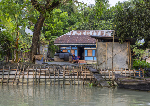 Bangladeshi woman washing cooking dishes on the river bank in Sundarbans, Barisal Division, Banaripara, Bangladesh