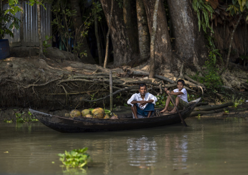 Bangladeshi man with his son carrying coconuts on a boat, Barisal Division, Banaripara, Bangladesh