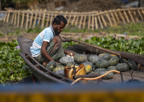 Bangladeshi man selling pumpkins at weekly floating market, Barisal Division, Harta, Bangladesh