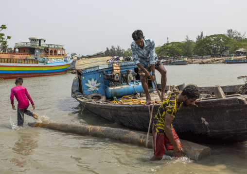 Bangladeshi men attaching a tree trunk to their boat, Barisal Division, Nesarabad, Bangladesh