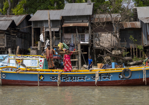 Bangladeshi family on a boat anchored in front of houses in Sundarbans, Barisal Division, Nesarabad, Bangladesh