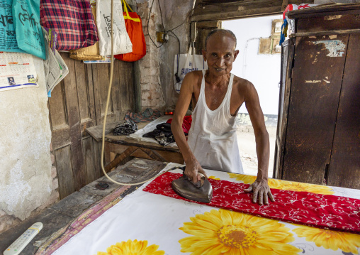 Old bangladeshi man ironing in a small shop, Rajshahi Division, Puthia, Bangladesh