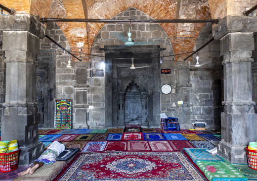 Bangladeshi man sleeping on carpets inside Kusumba mosque, Naogaon District, Manda Upazila, Bangladesh