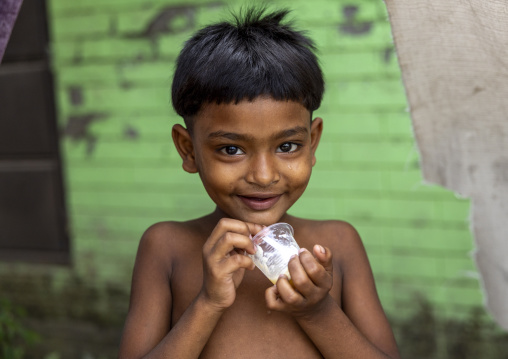 Portrait of a bangladeshi shy boy eating a desert, Dhaka Division, Rupganj, Bangladesh