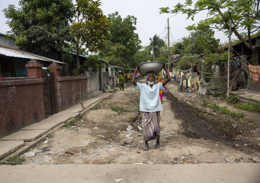 Bangladeshi old man carrying a basin  on his head in the street, Dhaka Division, Rupganj, Bangladesh