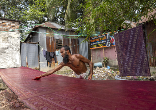 Bangladeshi man putting wax on fabric, Dhaka Division, Rupganj, Bangladesh