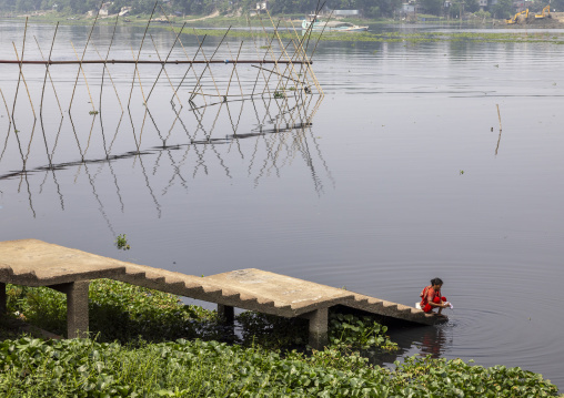 Bangladeshi woman washing clothes in a river, Dhaka Division, Rupganj, Bangladesh