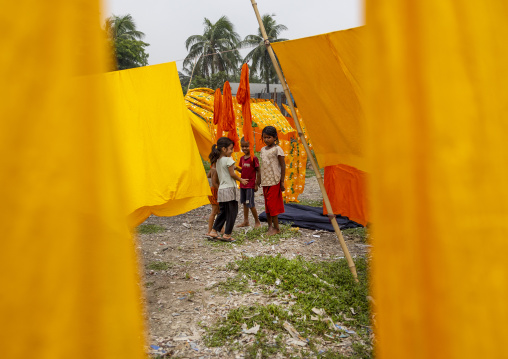 Bangladeshi children in the middle of drying fabrics, Dhaka Division, Rupganj, Bangladesh