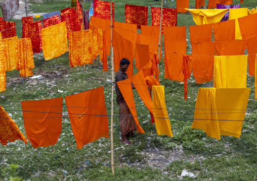 Bangladeshi worker hanging orange fabrics under the sun, Dhaka Division, Rupganj, Bangladesh