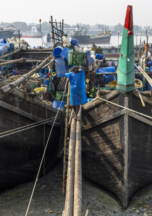 A bangladeshi porter carries a load from a trawler at the morning fish market, Chittagong Division, Chittagong, Bangladesh