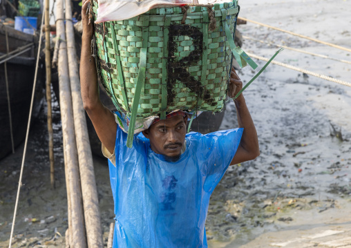 A bangladeshi porter carries a load at the morning fish market, Chittagong Division, Chittagong, Bangladesh