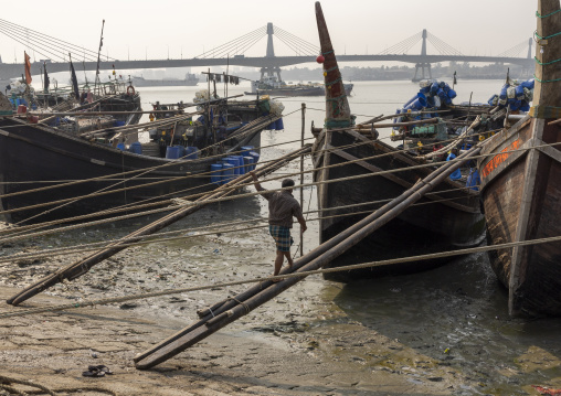 Bangladeshi man walking on pole to go on a trawler, Chittagong Division, Chittagong, Bangladesh