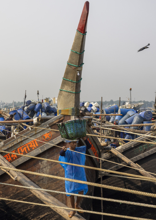 A bangladeshi porter carries a load from a trawler at the morning fish market, Chittagong Division, Chittagong, Bangladesh