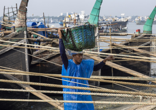 A bangladeshi porter carries a load from a trawler at the morning fish market, Chittagong Division, Chittagong, Bangladesh