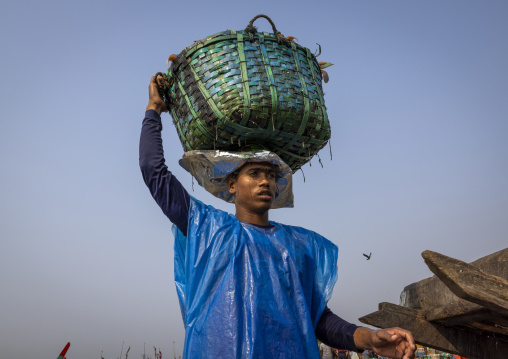 A bangladeshi porter carries a load at the morning fish market, Chittagong Division, Chittagong, Bangladesh